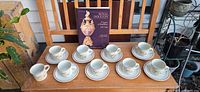 Full lot view of eight mug-saucer sets and book
