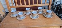 Six cup and saucer sets arranged on table