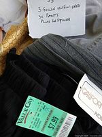Retail tag on ribbed black pants and handwritten lot note