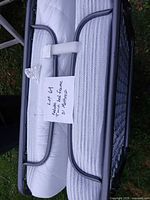 Folded rollaway bed showing grey metal frame and mattress secured upright