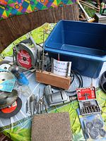 Overview showing circular saw, drill bits in wooden block, blue tote, saw blades and accessories on table