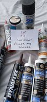 Overview of several caulk tubes, spray can and note