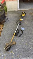 Full view of DeWalt string trimmer with strap and line spool on driveway
