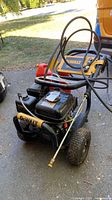 Overall view of DeWalt pressure washer with hose, wand, and red gas can
