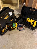 Group view showing DeWalt tool bag, reciprocating saw in case, sander, sanding discs