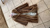 Full view of brown mink fur coat laid flat