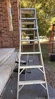 Full view of aluminum multi-position ladder standing in A-frame position with 2-step stool behind