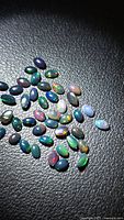 Loose Ethiopian black opal oval cabochons spread on black surface