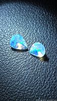 Pair of pear-cut opals showing multicolor flash against dark background