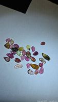 Group of assorted colored leaf-cut tourmalines on white background