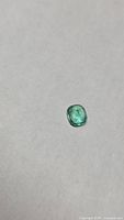 Full view of cushion-cut emerald on neutral background