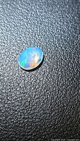 Oval faceted Ethiopian opal on textured black surface