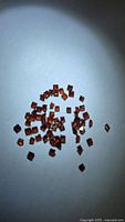Group of small square orange-red garnets spread on white background