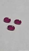 Three oval faceted rubies on neutral background