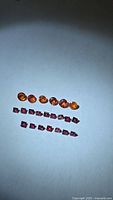 Group of orange sapphires and square rubies under light