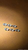 Six oval aquamarine stones on brown surface