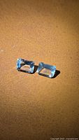 Pair of emerald-cut aquamarine gemstones on brown background
