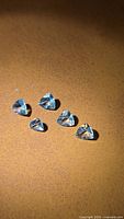 Five triangular light-blue aquamarine gemstones on brown surface