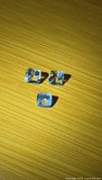 Three cushion cut aquamarines arranged on wooden surface