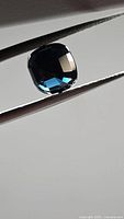 Cushion-cut deep blue spinel held by tweezers