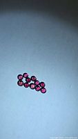 Group of 10 round red-pink cabochon rubies on white background