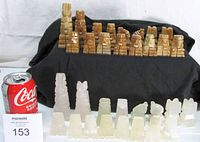 All 32 onyx chess pieces arranged with soda can for scale