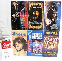 Front view of six VHS tapes with titles visible next to soda can for scale