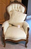 Front view of walnut Queen Anne armchair with matching pillow showing upholstery and tufting