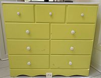 Front view of yellow dresser showing nine drawers and white knobs