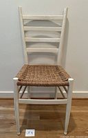 Front view of ladder-back chair showing white painted wood frame and woven seagrass seat