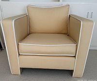 Front view of one chair showing upholstery, piping, cushion