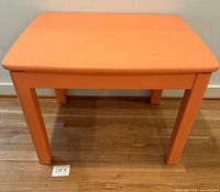 Front view of orange rectangular table showing legs and top surface wear
