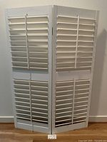 Front view of hinged white louvered panels standing in V formation