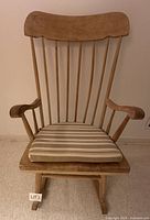 Front view of wooden rocking chair showing seat cushion and spindled back