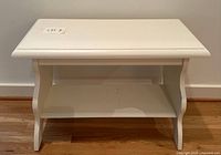 Front view of white painted wood side table showing lower shelf and curved sides