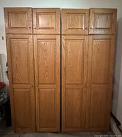 Front view of both oak storage cabinets showing eight doors