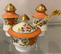 Front view of set showing mustard pot with spoon and two shakers
