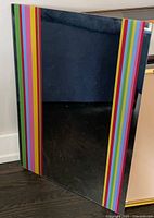 Front view of mirror showing rainbow striped borders and reflective surface