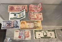 All eight banknotes displayed on glass surface