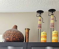 overview of pot, candle holders, brass vase, pillar candles on cabinet
