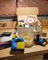 Overview of tapes, stretch wrap, twine and sanding items on bench