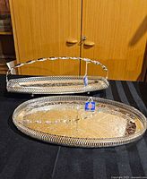 Two silver-plated trays on table, oval and rectangular with handle