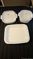 Top view of three Corning Ware dishes: two lidded square casseroles and one rectangular dish