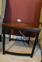 Full view of metal frame end table with wood top against wall