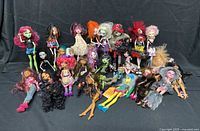 Group shot of all 26 Monster High dolls on black backdrop