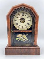 Front view of New Haven wooden mantel clock showing dial and lower bird panel