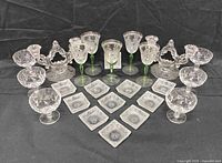 Full lot showing all stemware, plates, and candlesticks on black backdrop