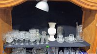 Shelf showing assorted iridescent and clear crystal stemware, bowls and platters