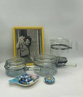 Overall lot showing Pyrex cookware, percolator, marbles in dish, paperweight, framed photo