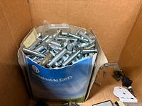Box of numerous steel bolts and screws held in paper sleeve